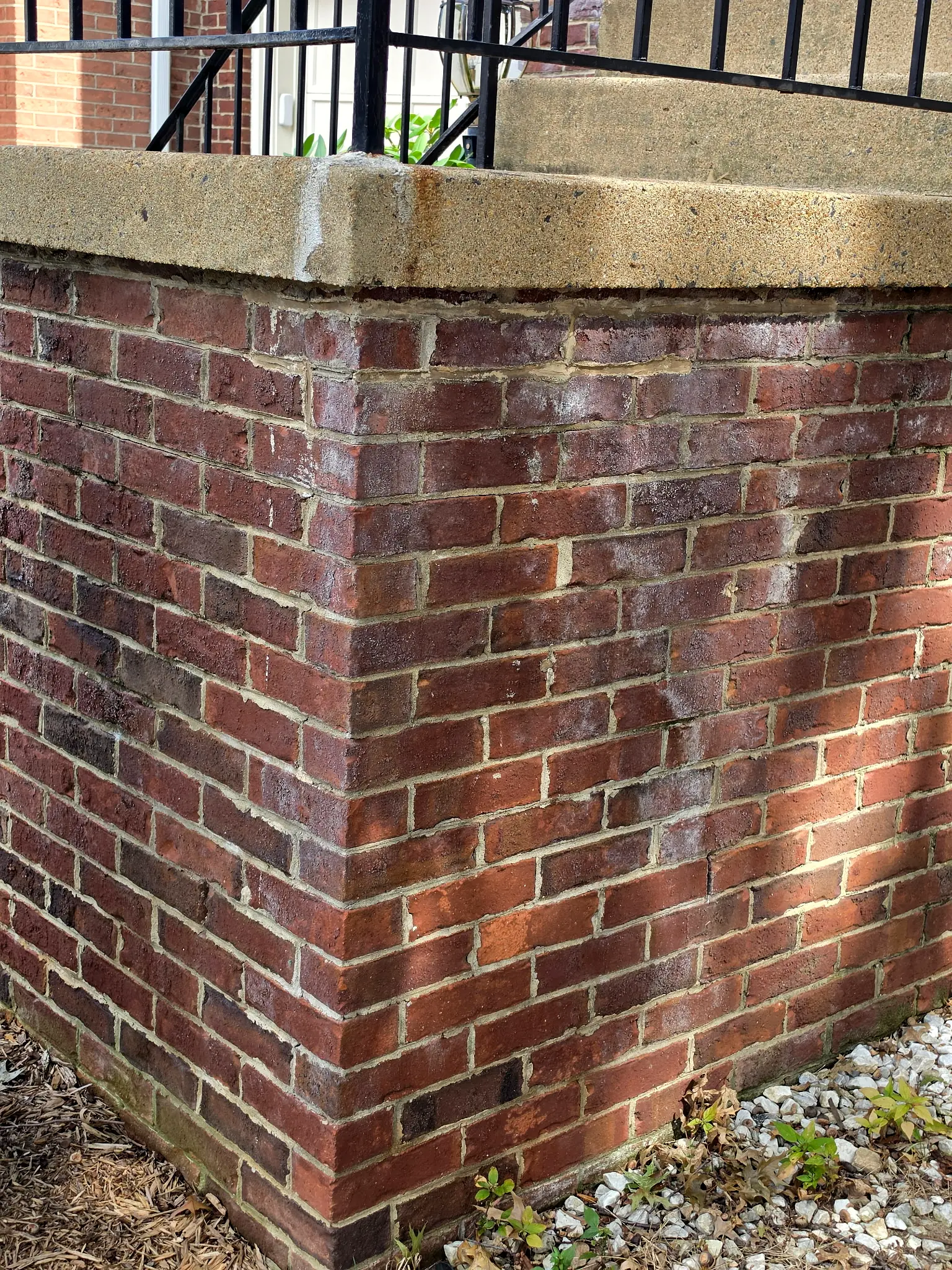 Before: Brick pier under a concrete cap, streaked with a white haze and dark staining
