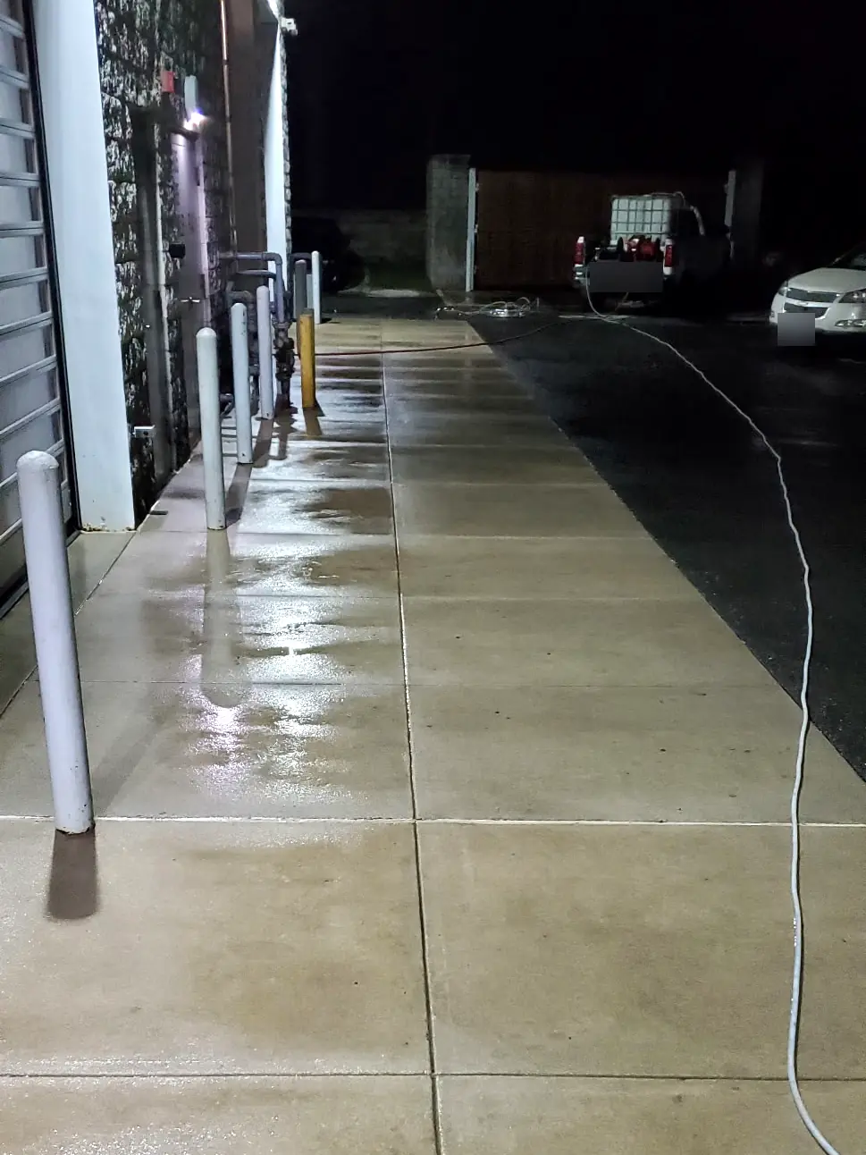 After: The same commercial walkway after night pressure washing, clean and still wet, with our rig parked beyond