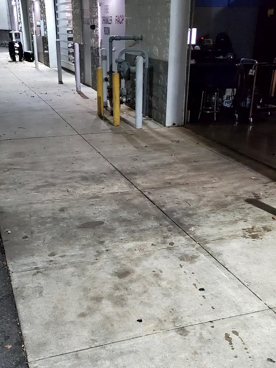 Before: Concrete walkway behind a commercial building at night, spotted with oil stains and dark grime