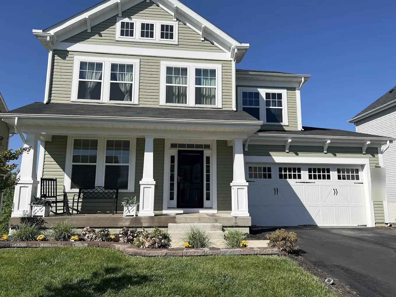 Two-story home with green vinyl siding and white trim after a house wash