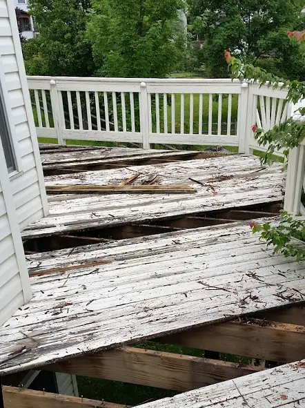 Before: Deck with rotted, weathered boards pulled up to expose the joists