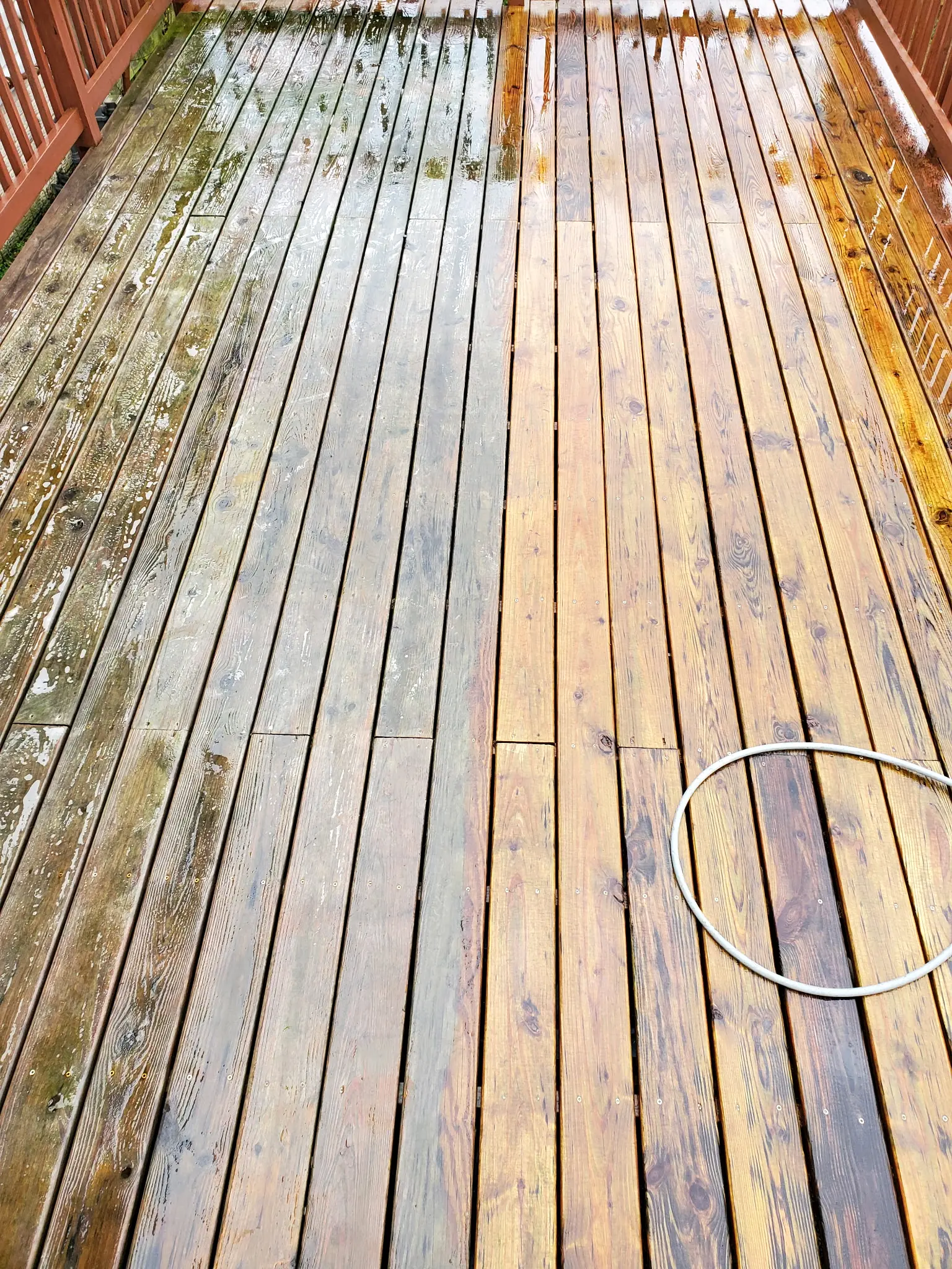 Wood deck mid-cleaning: the left boards still gray and green with mildew, the right boards washed back to bare wood