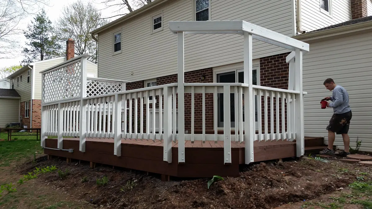 Crew member finishing a deck with a brown stained floor and freshly painted white railings