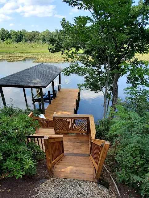 Stained wood stairs leading down to a covered boat dock on the water