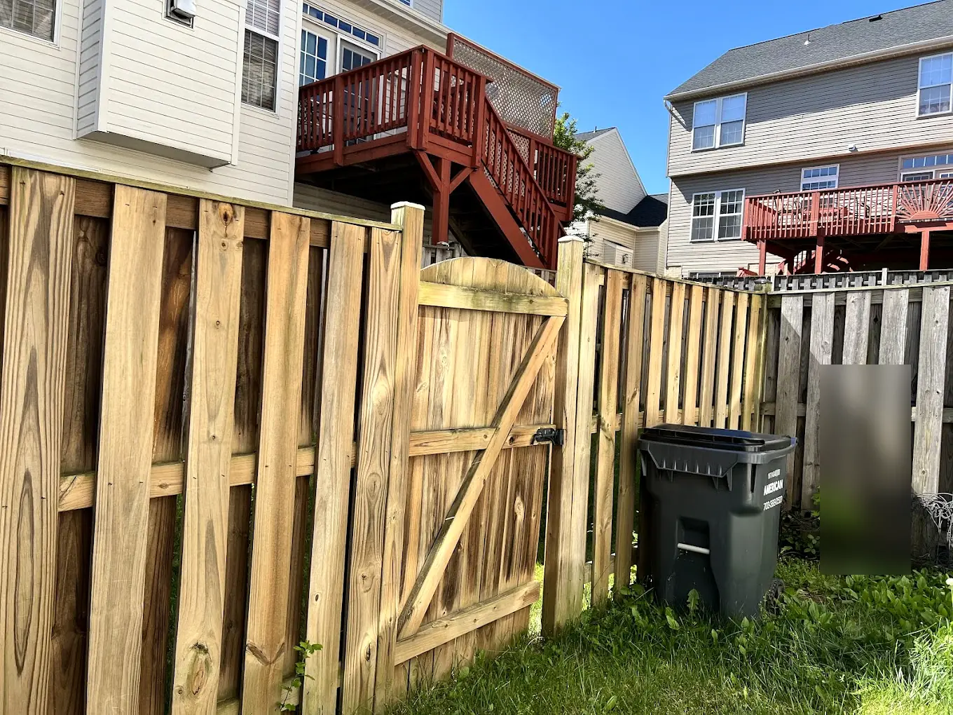 Wood privacy fence and gate after cleaning, with townhouse decks behind