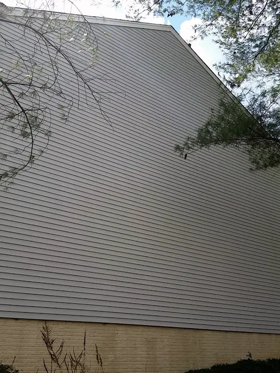 Tall gable wall of gray vinyl siding after soft washing
