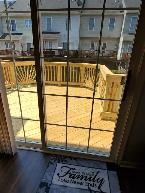 View through a sliding door onto a new pressure-treated deck with sunburst railings