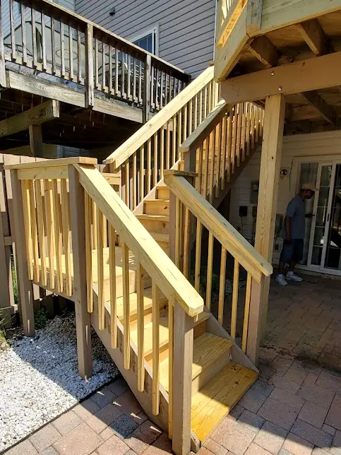 New pressure-treated deck stairs and railings over a paver patio