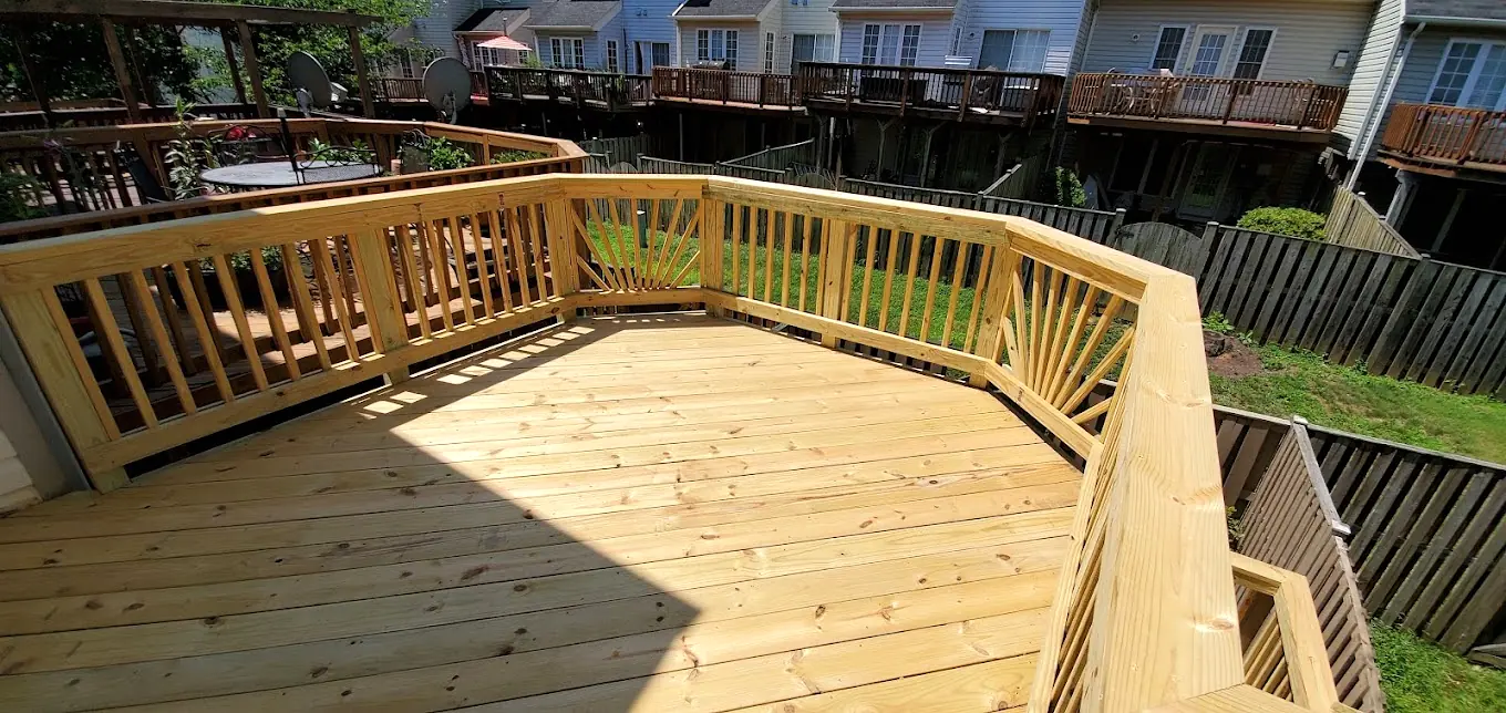 New pressure-treated deck with sunburst railing panels behind a row of townhouses