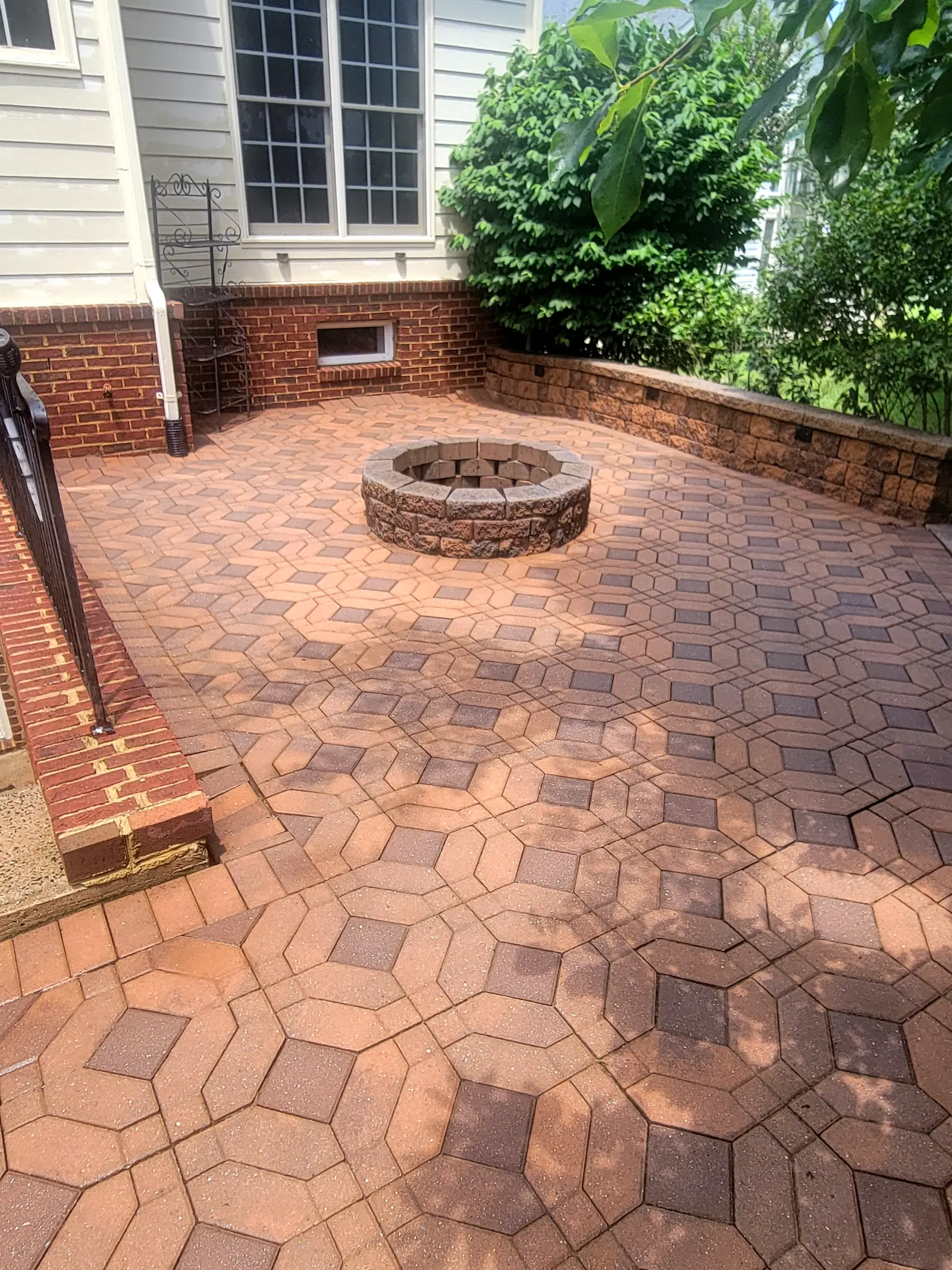 After: The same paver patio and fire pit after cleaning, with the pavers back to a warm red