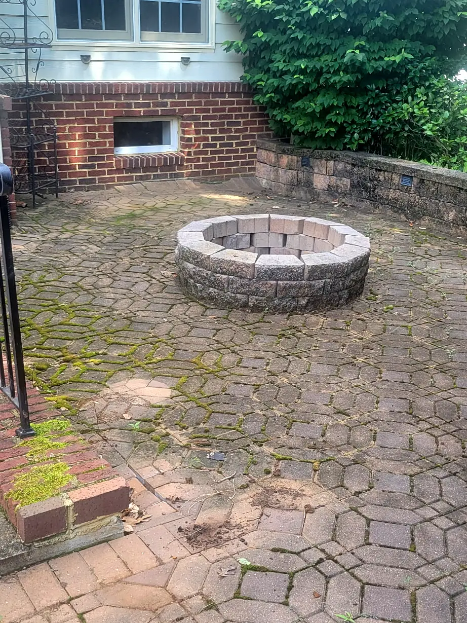 Before: Brick paver patio and round fire pit behind a house, with moss and dark growth filling the joints