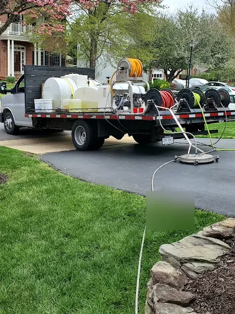 Ultimate Powerwash work truck with tanks and hose reels, and a surface cleaner on a driveway